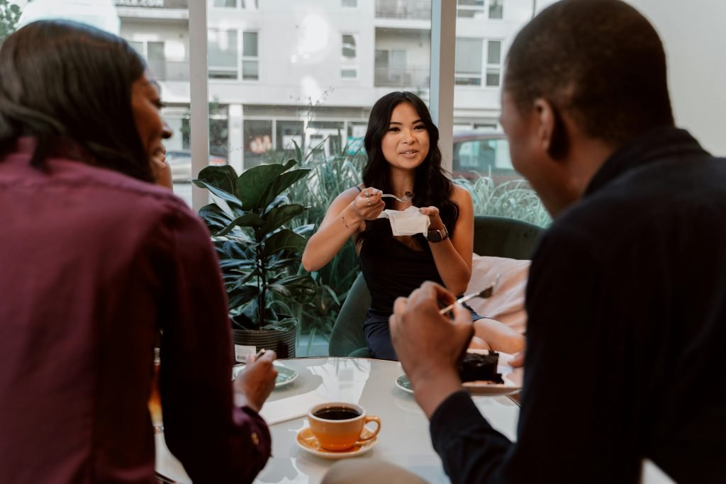 Diverse group of friends enjoying coffee and cake in a modern café. Perfect for lifestyle and social themes.
